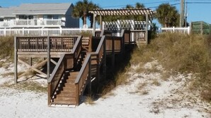 A wooden staircase leading to a beach house with a white fence and palm trees in the background. - Beachy Keen #501 Free Beach Svc 2 Chairs and Umbrella 2Bd 2Bath 1st Fl (Destin)
