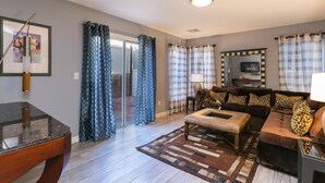 Un salon comprenant un canapé, une table basse et un téléviseur. Une porte vitrée donne accès à un balcon.