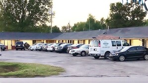 Un motel doté de nombreuses chambres, d’un parking et d’une rangée de voitures garées.