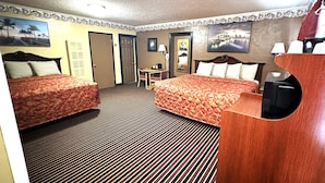 A hotel room with two beds, a desk, a chair, a TV, and a view of the cityscape. - Relax Inn (Vinita)