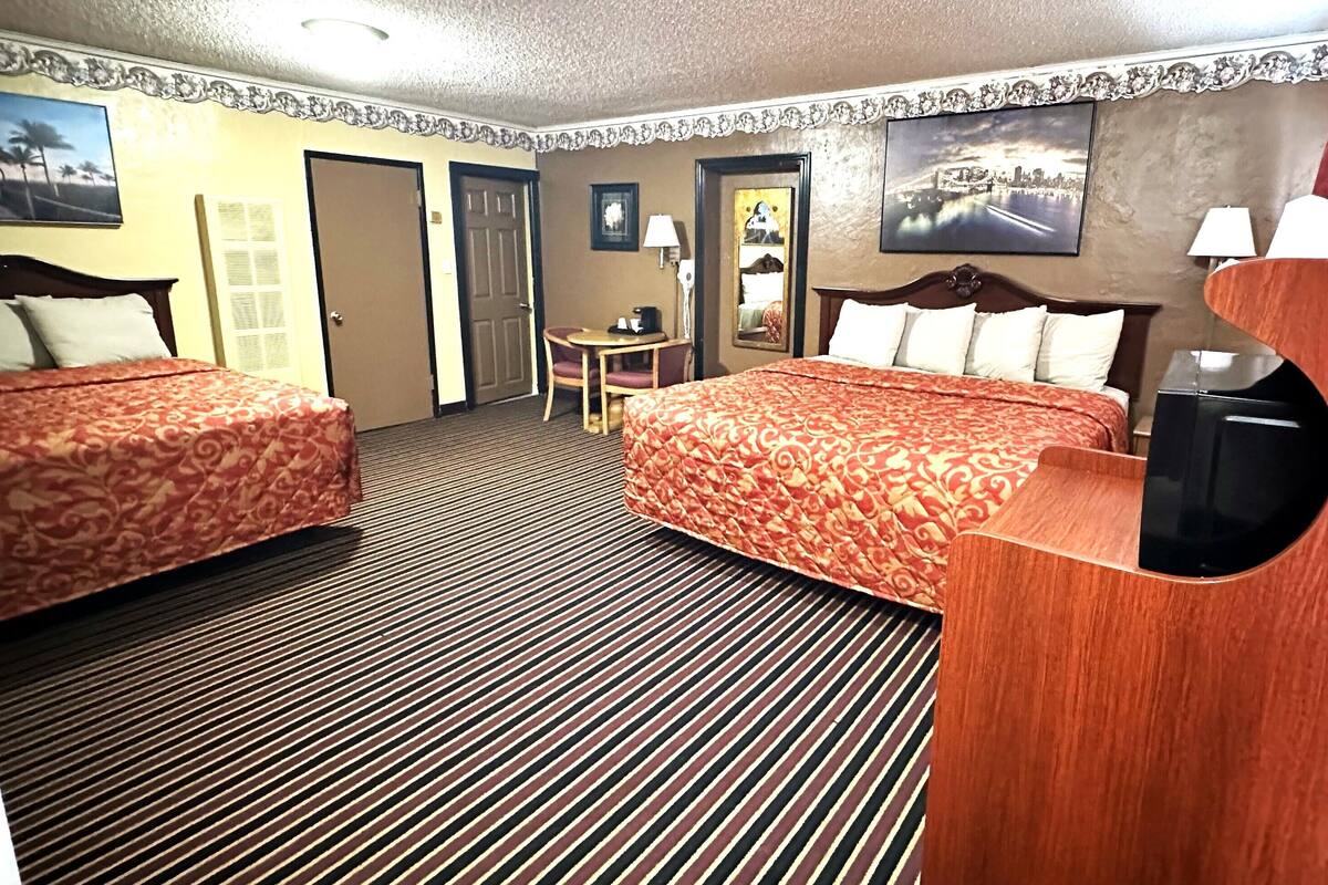 Une chambre d’hôtel avec deux lits, un bureau, une chaise, une télévision et une vue sur le paysage urbain.