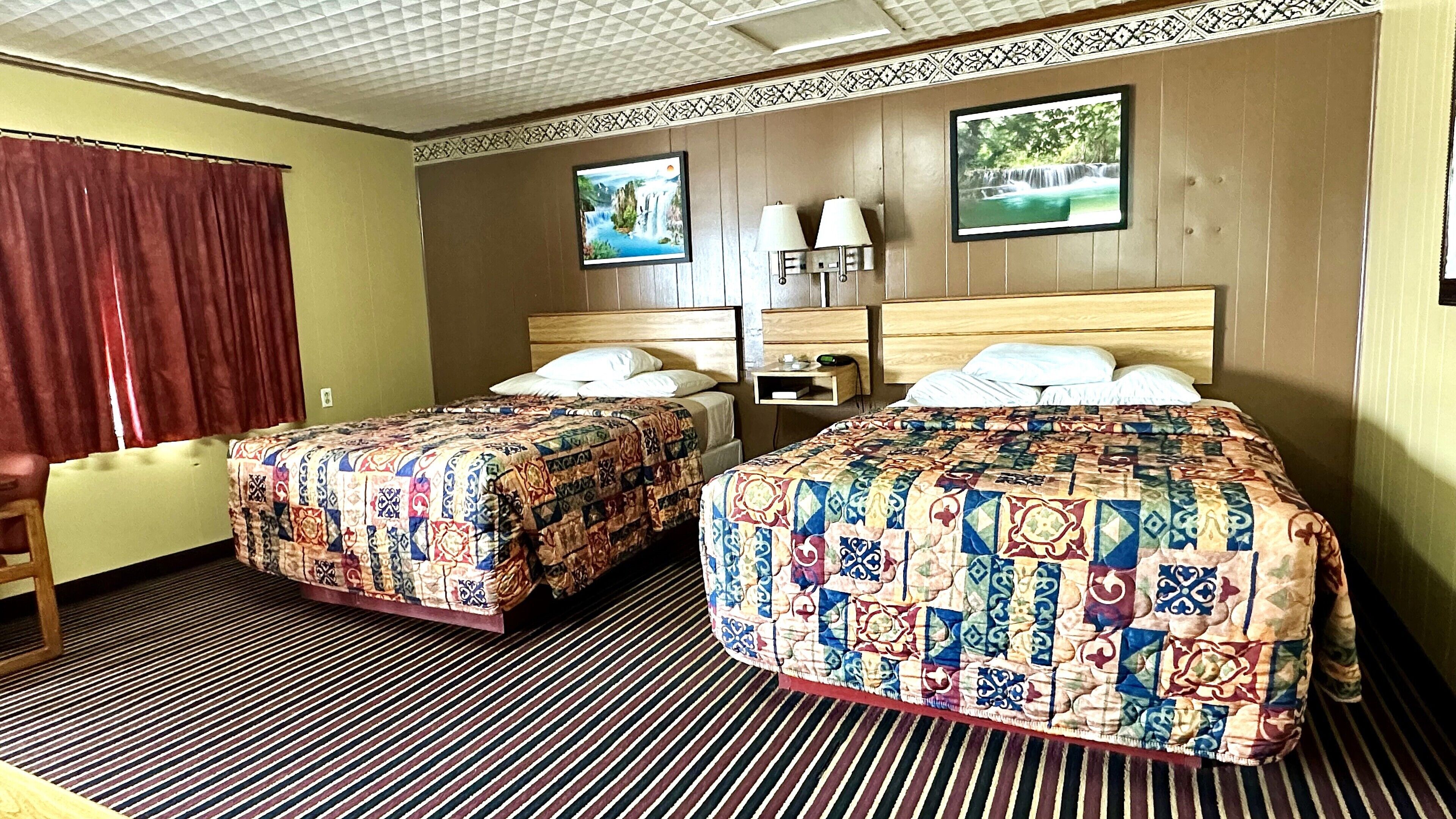 A hotel room with two beds, a desk, a chair, and a TV on the wall.