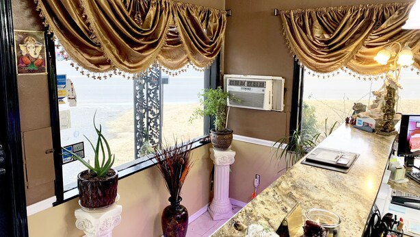 A room with a view of the beach, a bar area with a laptop, decorative plants, and a small statue. - Relax Inn (Vinita)