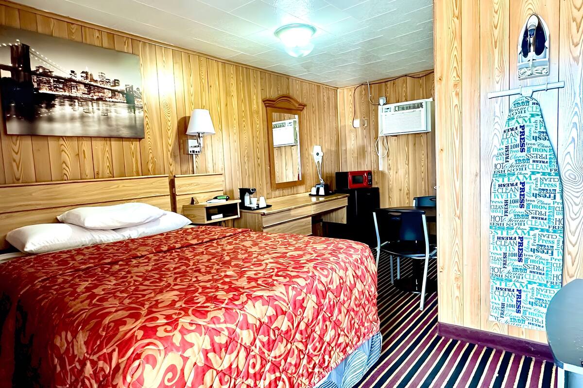 Une chambre d’hôtel avec un grand lit, un bureau avec une chaise, un four à micro-ondes et un téléviseur fixé au mur.