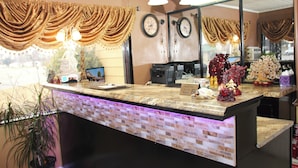 A reception area with a marble counter, two clocks on the wall, and a sign that says "Thank You... And Good Night." - Relax Inn (Vinita)