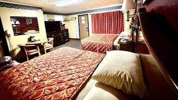 Una camera d'albergo con due letti, una scrivania, una sedia, una televisione e un comò.
