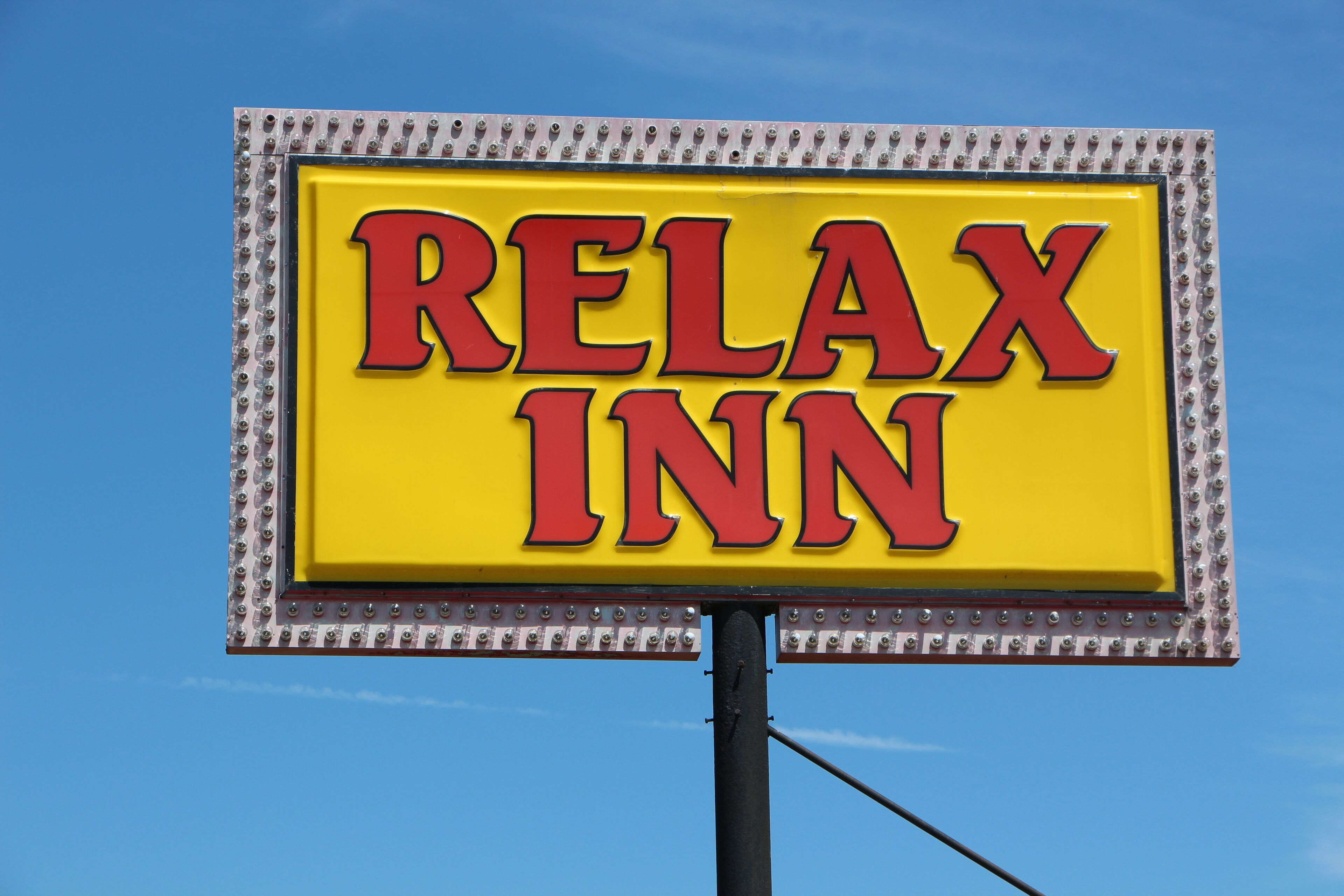 A yellow sign with red lettering that reads "RELAX INN".