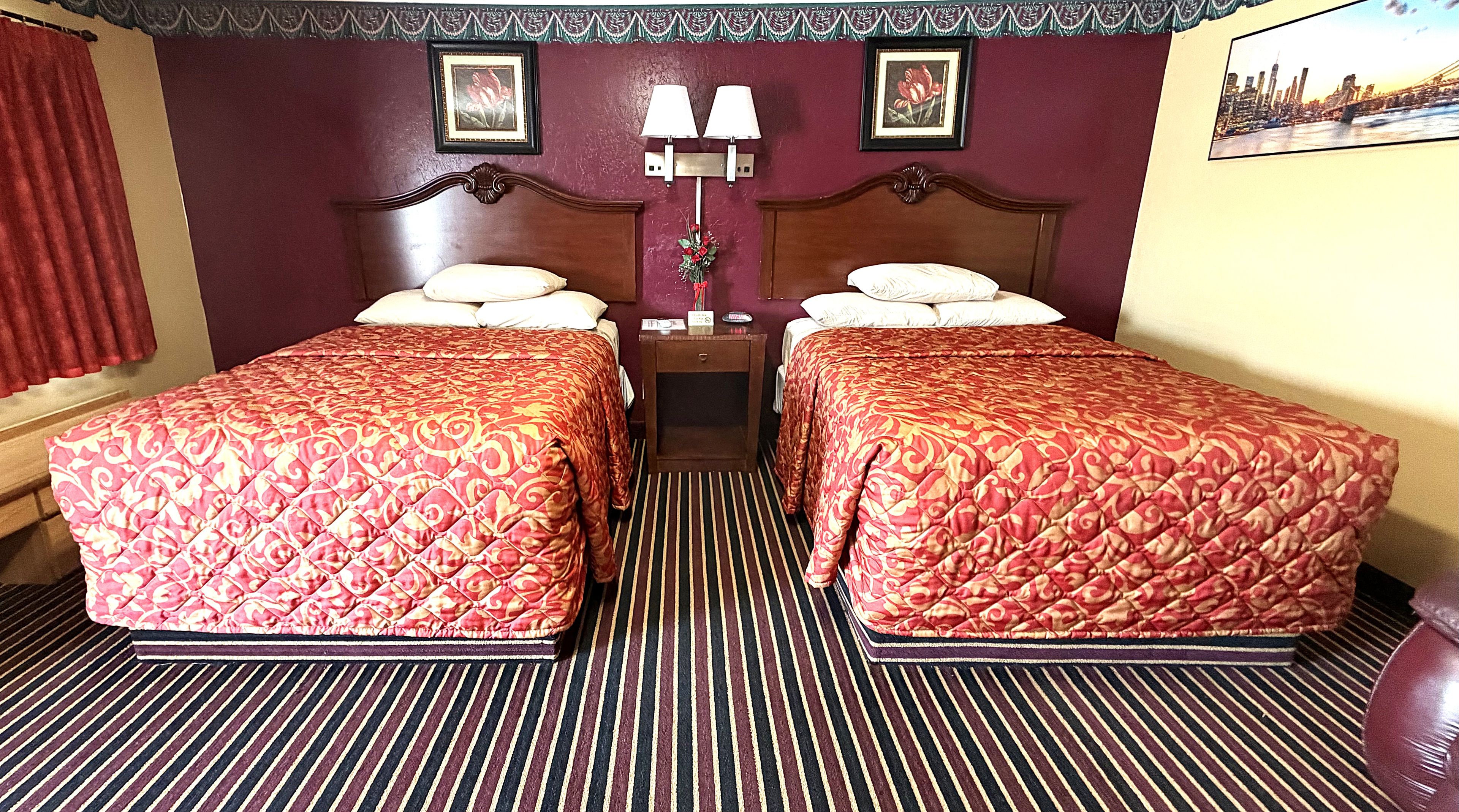 Een hotelkamer met twee bedden, een nachtkastje met lampen en uitzicht op de stad.