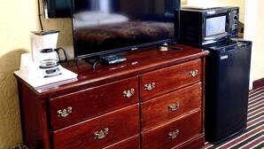 A wooden dresser with a flat-screen TV, a coffee maker, and a microwave. - Relax Inn (Vinita)