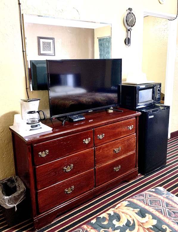 Un aparador de madera con un televisor de pantalla plana, una cafetera y un microondas.