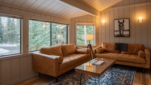 A cozy living room with two leather sofas, a glass coffee table, and a patterned rug.
