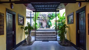 A covered entrance with a stone staircase leading to a door, surrounded by potted plants and a view of a mountain. - Mad Monkey Luang Prabang (Luang Prabang)