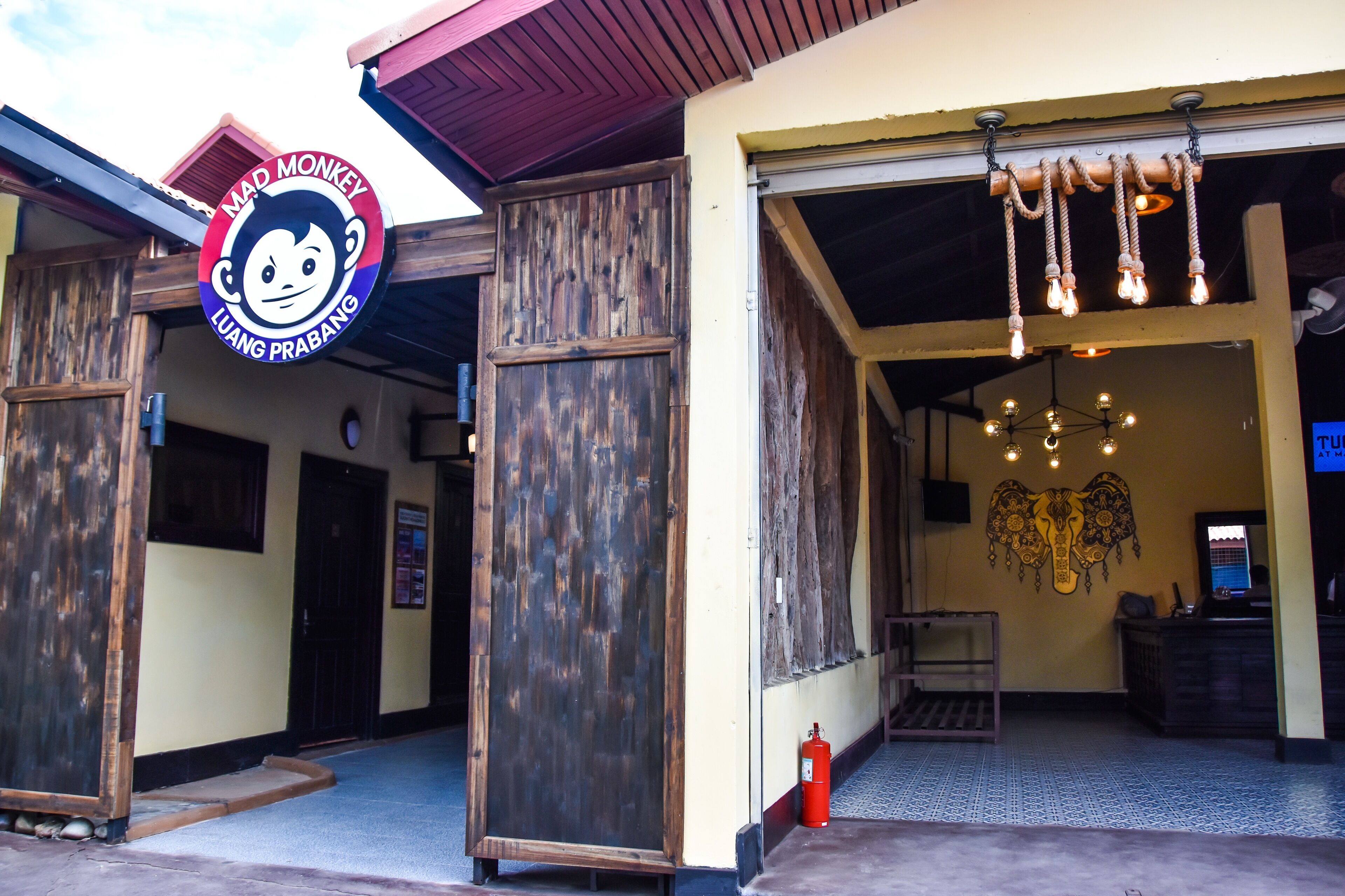 Un edificio con un letrero que dice "Mad Monkey Luang Prabang" y una puerta de madera.