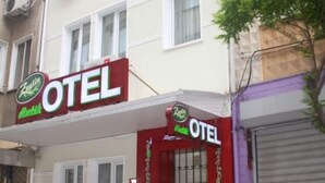 Un hôtel avec une entrée rouge, une enseigne indiquant « OTEL » et une enseigne verte « Zenita » au-dessus de l’entrée.