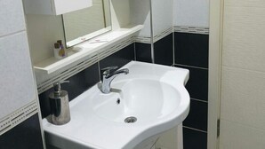 Une salle de bain avec un lavabo blanc, un miroir au-dessus et un meuble en dessous.