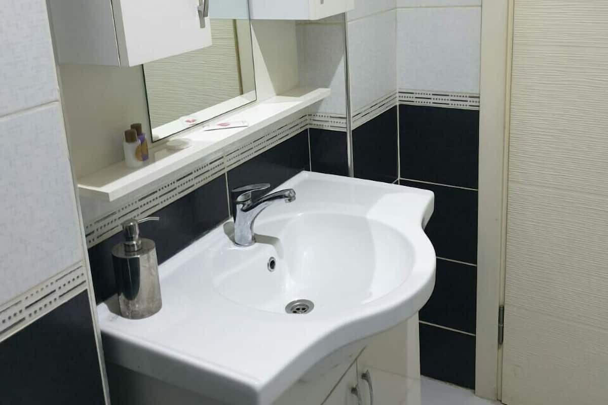 A bathroom with a white sink, a mirror above it, and a cabinet below.