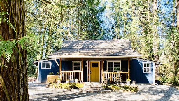 A small, single-story house with a porch, surrounded by trees. - Luxury Cottage in the Woods with Movie Theater!  (Auburn)