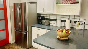 A modern kitchen with white cabinets, stainless steel appliances, and a black countertop. - Luxury Cottage in the Woods with Movie Theater!  (Auburn)