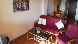 Ein Wohnzimmer mit einem roten Sofa, einem Glastisch und einem Gemälde an der Wand.