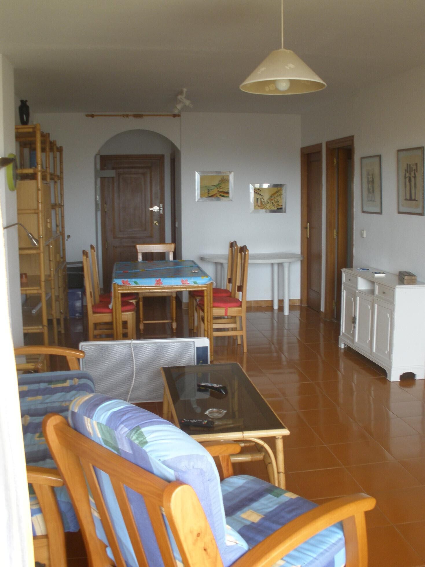 Un coin repas comprenant une table et des chaises, un canapé, une petite table avec une télécommande et un meuble.