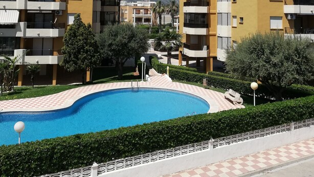 A modern apartment complex with a swimming pool, surrounded by greenery and a clear blue sky. - La Marina I 4º Solo Familias! (Xeraco Playa)
