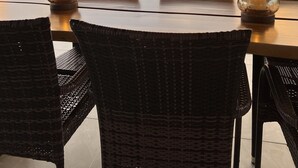 Un coin repas avec des chaises en osier et une table, offrant une vue imprenable sur un paysage luxuriant et un coucher de soleil.
