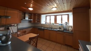 Una cocina con armarios de madera, salpicadero de azulejos, una ventana con persianas y una encimera con varios electrodomésticos.