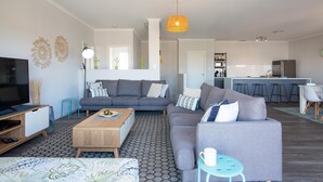 Una sala de estar moderna con un sofá gris, una mesa de centro de madera y un mueble para televisión.