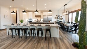 Una cocina amplia con una isla grande, taburetes de bar e iluminación colgante.