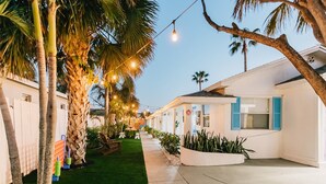 A row of white buildings with blue shutters, surrounded by palm trees and artificial lighting.