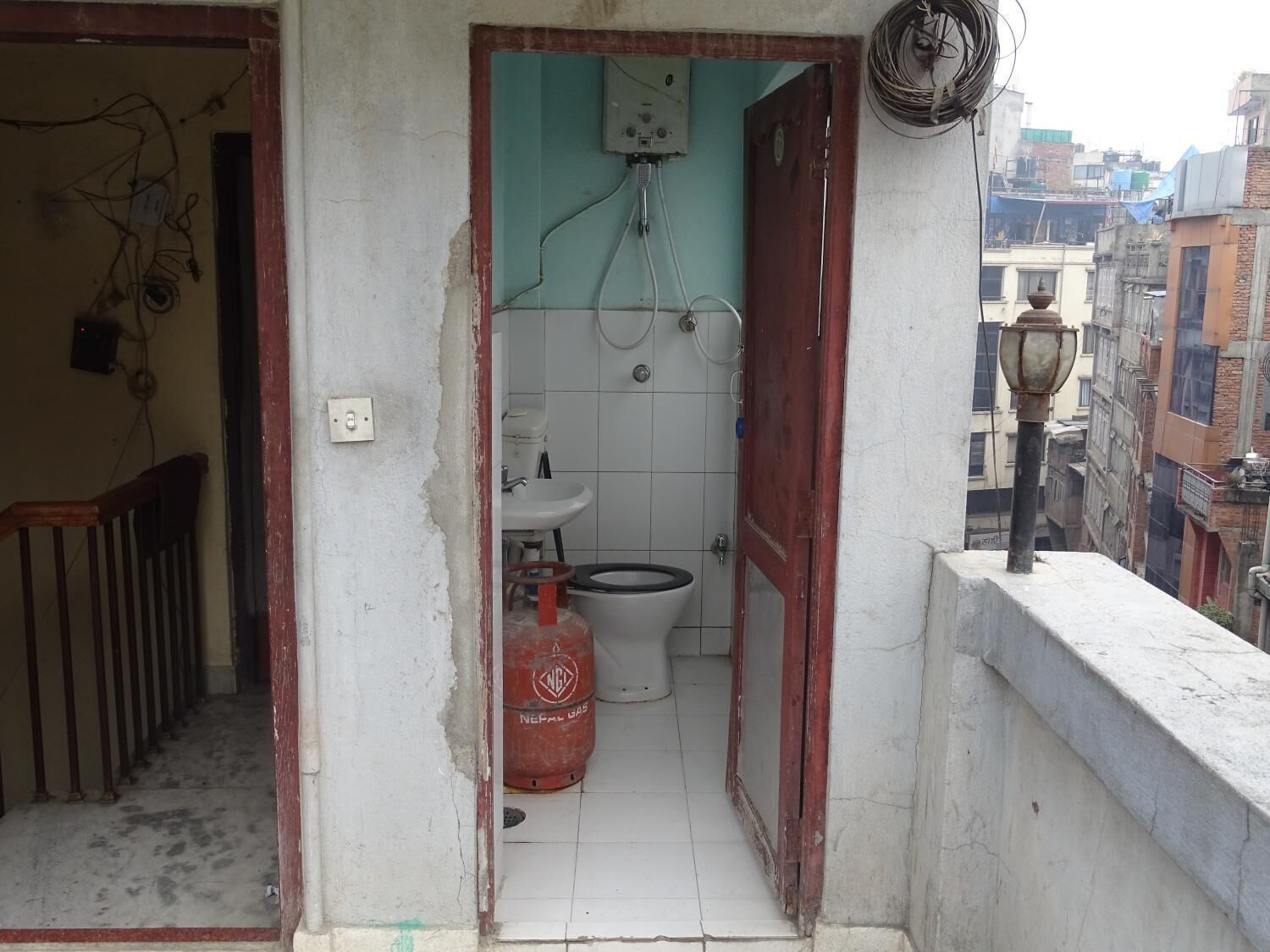 Une petite salle de bain compacte, équipée de toilettes, d’un lavabo et d’un chauffe-eau.
