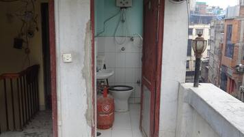 Une petite salle de bain compacte, équipée de toilettes, d’un lavabo et d’un chauffe-eau.