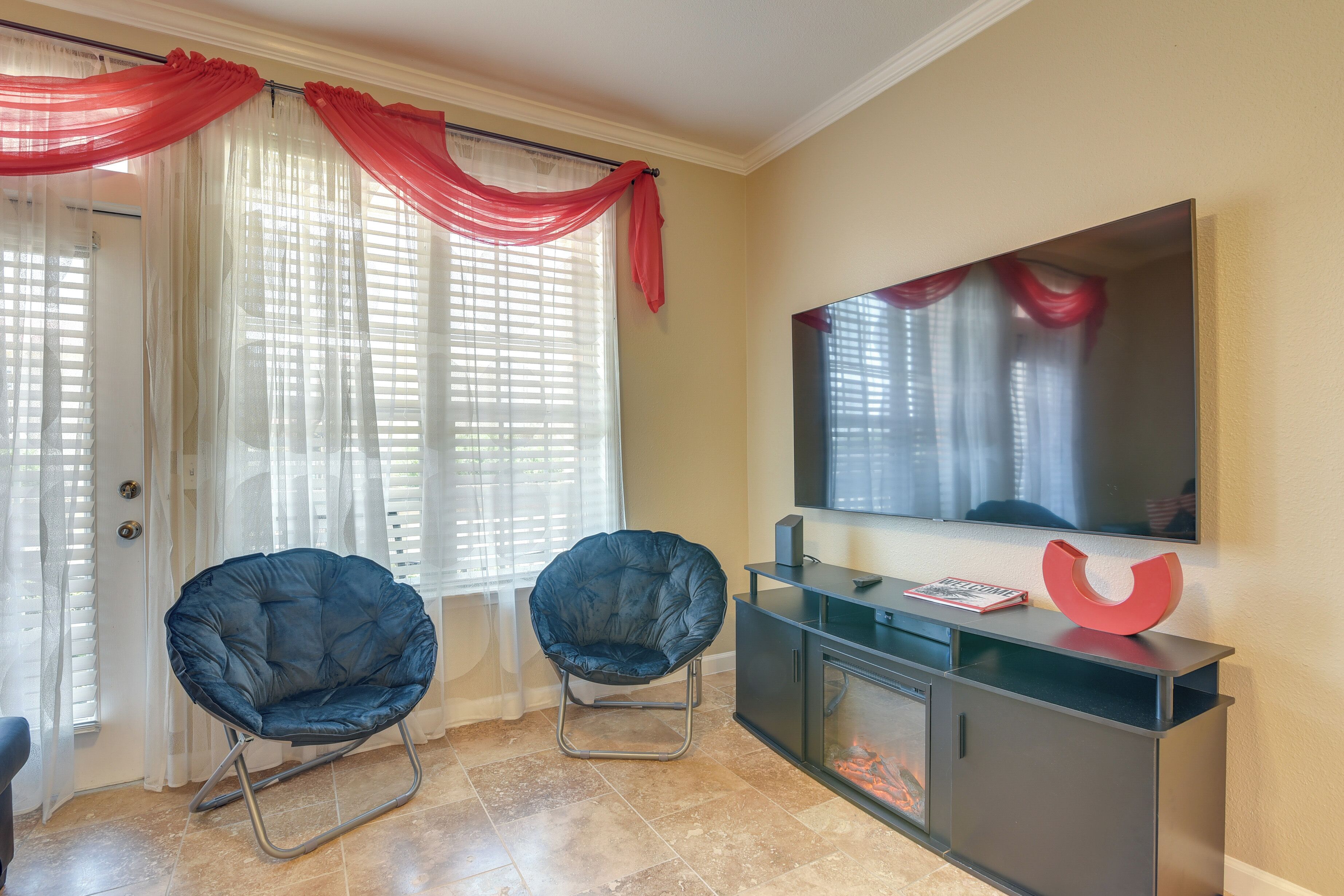 A room with two black chairs, a glass cabinet with a red object, and a TV on the wall.