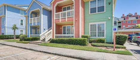 A row of colorful townhouses with a parking lot in front.