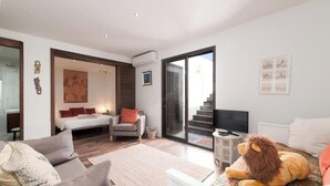 Una sala de estar moderna con un sofá, una silla, una cama, un televisor y un peluche grande.