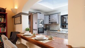 Una cocina moderna con una isla central, horno empotrado y un comedor con mesa y sillas de madera.