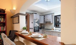 A modern kitchen with a wooden bar counter, built-in appliances, and a view of the dining area.