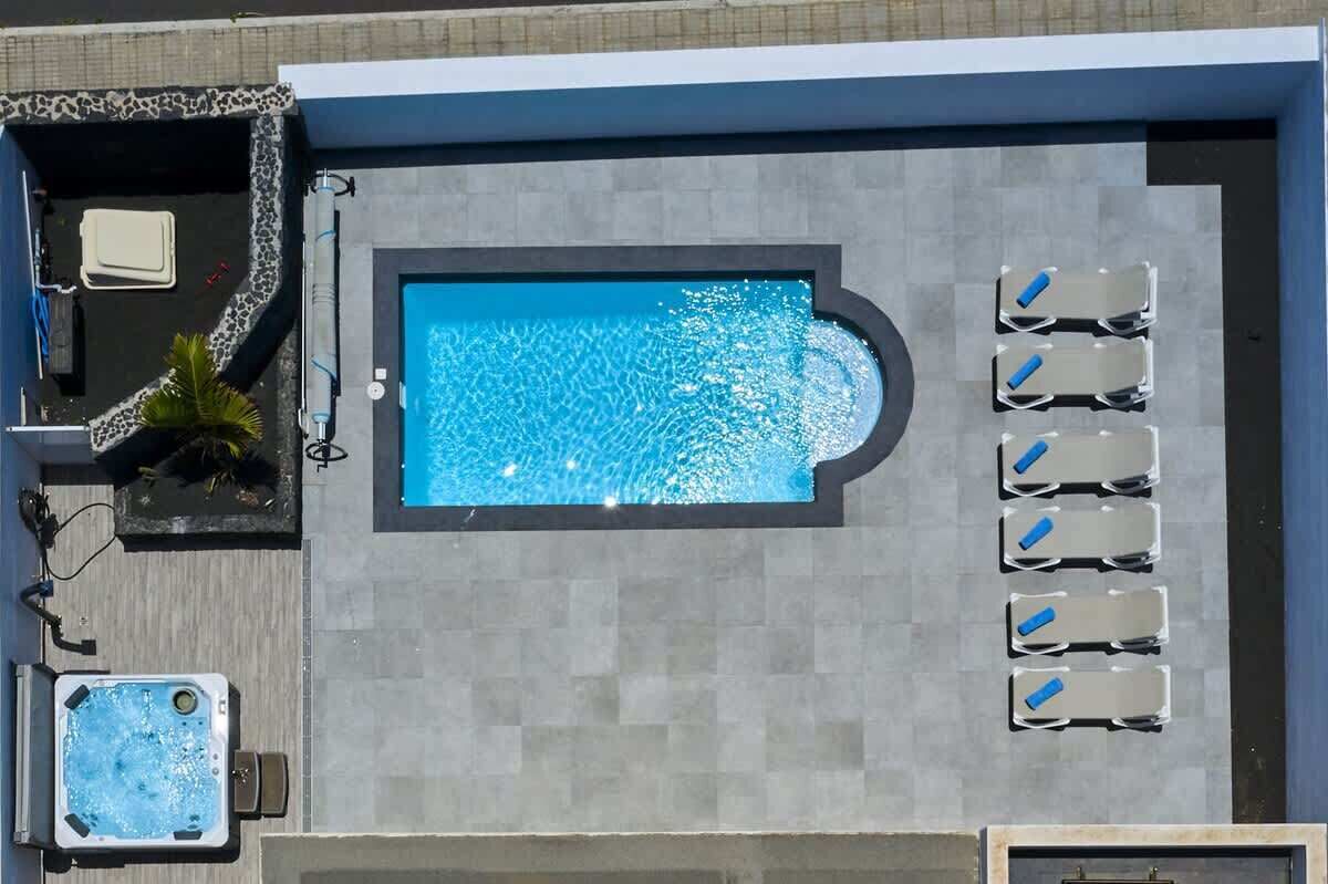 A rooftop pool with a hot tub, lounge chairs, and a small seating area.