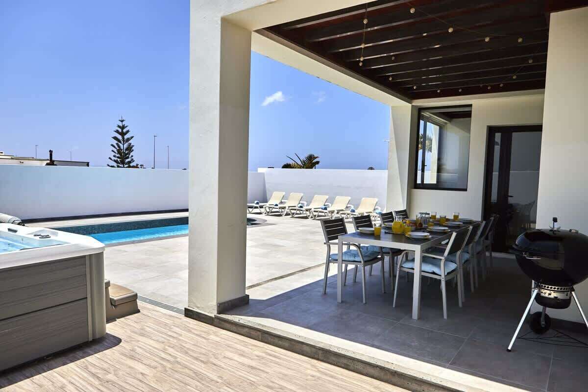 A rooftop terrace with a swimming pool, lounge chairs, a dining table, and a barbecue grill.
