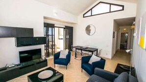 Una sala moderna con televisión, sofás y comedor.