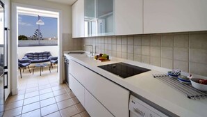 Una cocina moderna con horno empotrado, un ventanal grande y una zona de comedor con sofá y sillas.