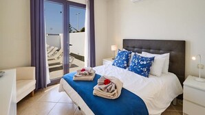Una habitación de hotel con cama, mesita de noche, silla y vistas a un balcón.