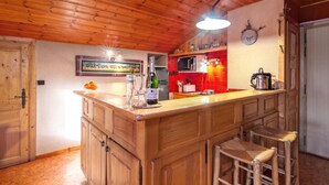 A wooden interior with a kitchen area featuring a bar, a microwave, and a clock on the wall. - La Persévérance15 - 2BR Sleeps 6 | Near Ski Lift & Mont Blanc Views, Argentière (Chamonix), France (Argentière (Chamonix))