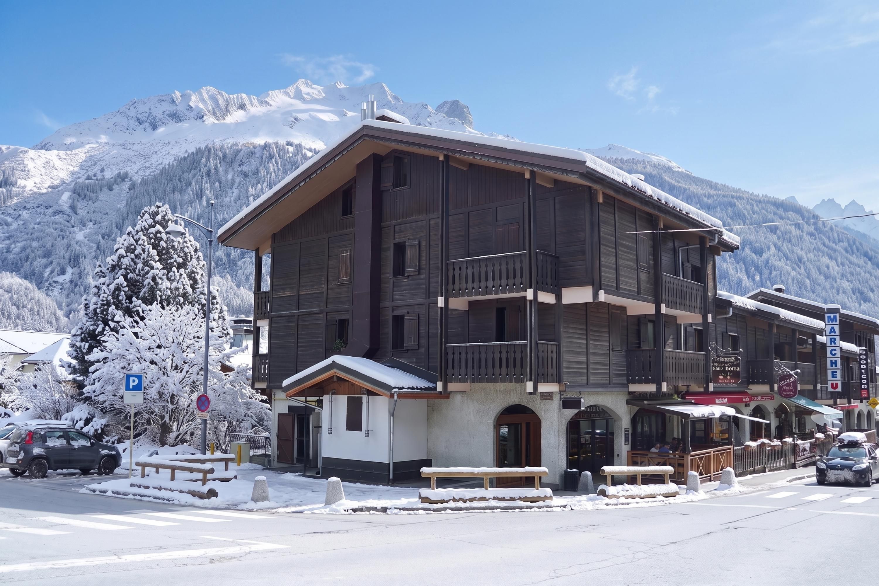 A multi-story wooden building with balconies, a ski resort backdrop, and a clear sky.
