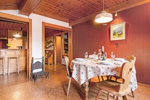 A dining area with a table set for four, wooden chairs, and a painting on the wall.