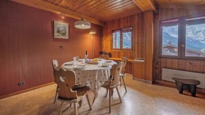 A wooden interior with a dining table set for four, a window with a mountain view, and a wooden ceiling. - La Persévérance15 - 2BR Sleeps 6 | Near Ski Lift & Mont Blanc Views, Argentière (Chamonix), France (Argentière (Chamonix))