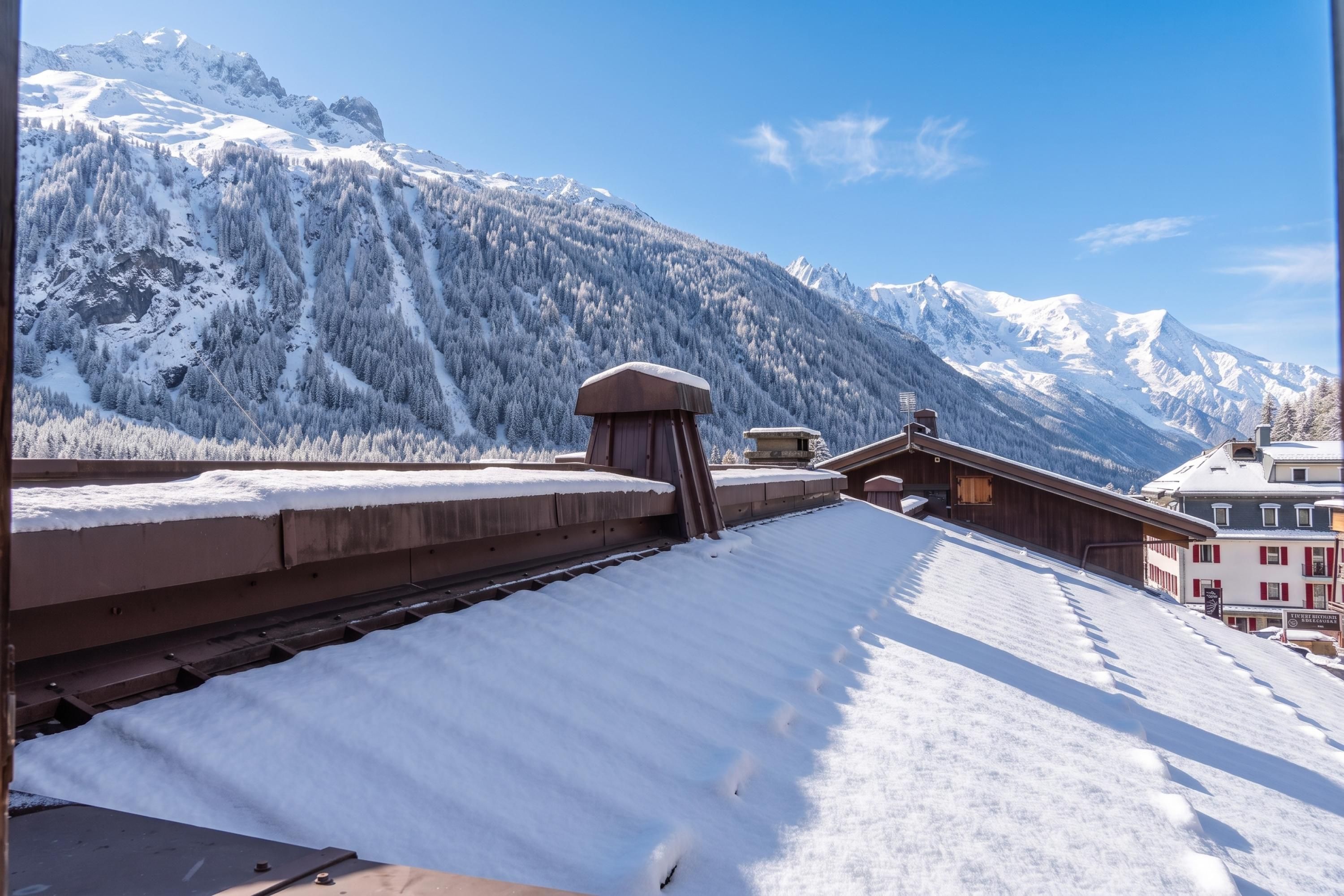 A snow-covered rooftop with a view of snow-covered mountains and a building with red shutters.