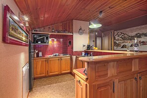 A kitchen with wooden cabinets, a microwave, and a red tiled backsplash.