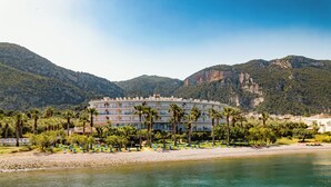 A hotel with a pool, surrounded by palm trees and mountains. - Sissy (Kamena Vourla)