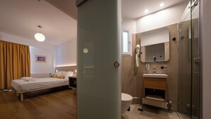 A modern hotel room with a bed, a bathroom with a shower, and a toilet. - Sissy (Kamena Vourla)